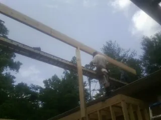 Carpenter setting a ridge beam over a new addition frame — Ice Dam Removal by Roofing Brothers in Gibsonville