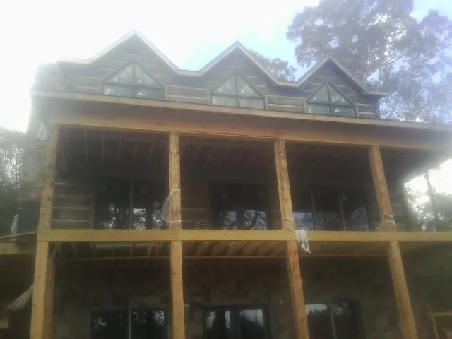 Dormers and porch framing on a large log home under construction — Roof Coating work by our crew in Gibsonville