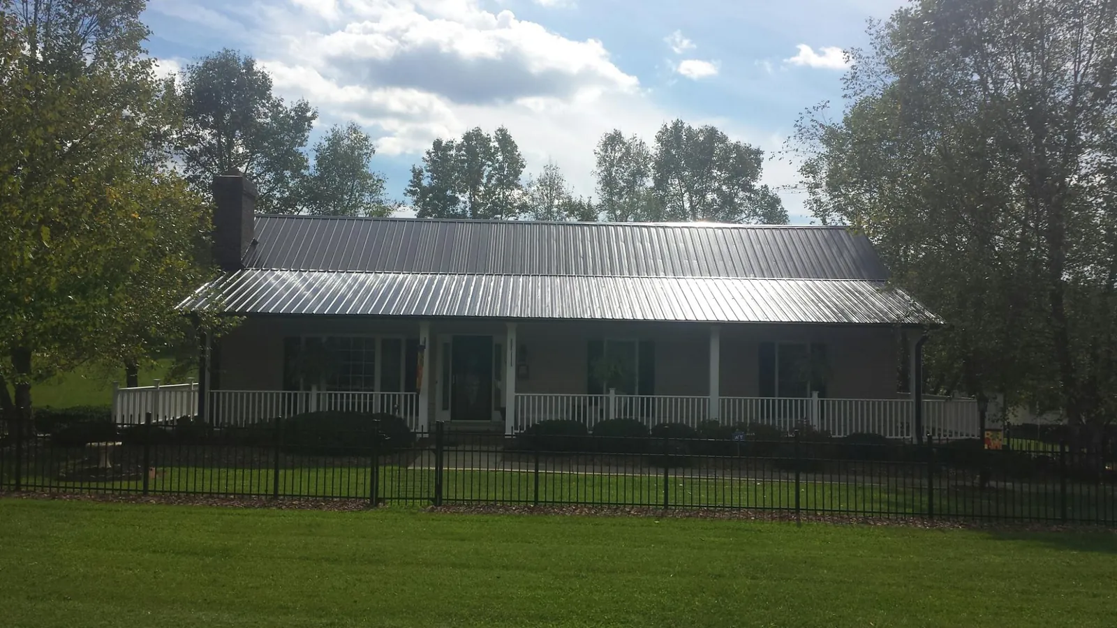 Gray metal roof on a brick ranch with a full width front porch — Gutter Guard Installation work by our crew in Gibsonville