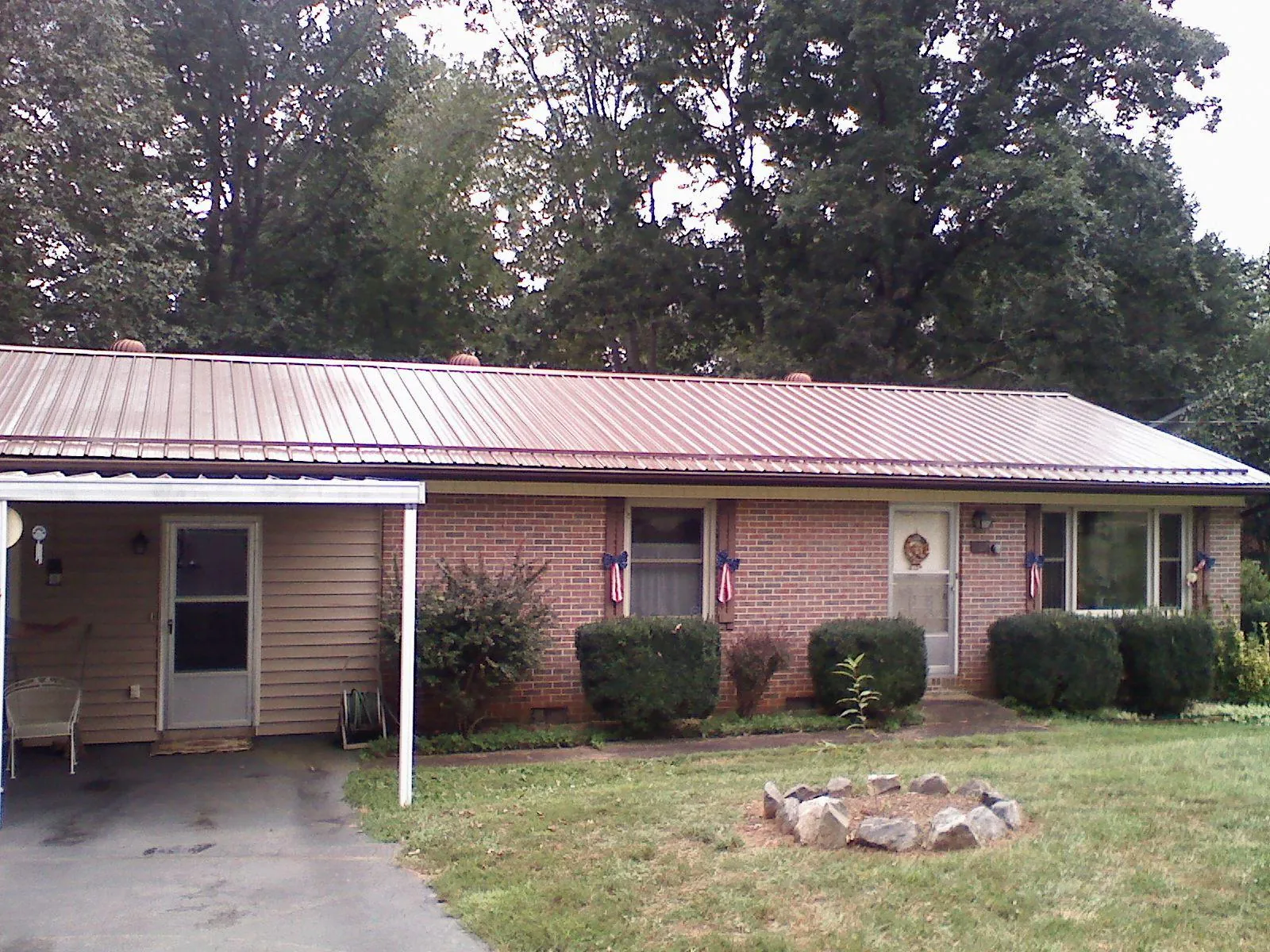 Bronze metal roof and carport on a brick ranch home — Roof Repair work by our crew in Gibsonville
