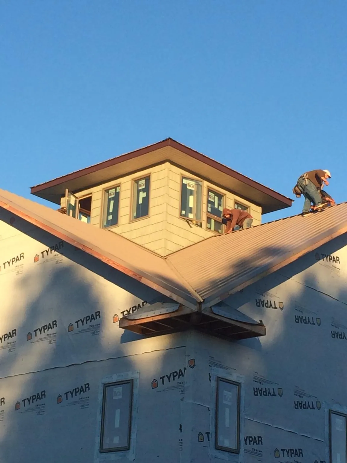 Roofers working around a rooftop cupola on a new metal roof at sunset — Roof Waterproofing in Gibsonville by Roofing Brothers